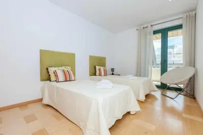 a white room with two beds and a chair at Marina Vilamoura - Aquamar 315 by Vilamoura Sun in Vilamoura
