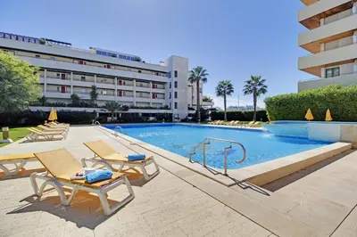 a swimming pool with tables and chairs and a building at Marina Sagres Apartment in Vilamoura