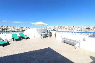 a patio with chairs and an umbrella and the ocean at Casa do Sol in Albufeira