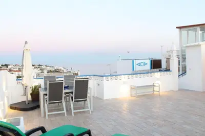a balcony with a table and chairs and an umbrella at Casa do Sol in Albufeira