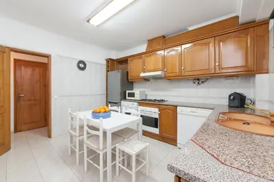 a kitchen with wooden cabinets and a white table at Vila dos Girassóis - BlueSea in Albufeira