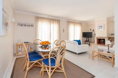 a living room with a table and chairs and a couch at Vila dos Girassóis - BlueSea in Albufeira