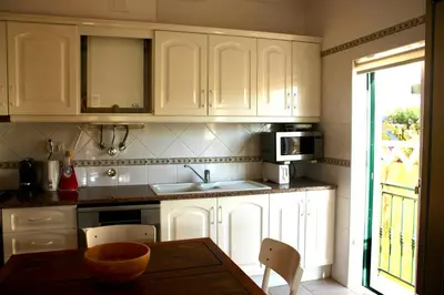 a kitchen with white cabinets and a wooden table at Encosta das Oliveiras 49D in Vilamoura