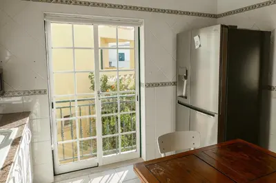 a kitchen with a refrigerator and a table and a window at Encosta das Oliveiras 49D in Vilamoura