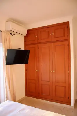a bedroom with wooden cabinets and a flat screen tv at Encosta das Oliveiras 49D in Vilamoura