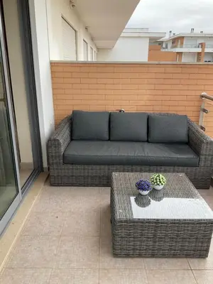 a couch on a patio with two vases on a table at Vila Branca in Albufeira