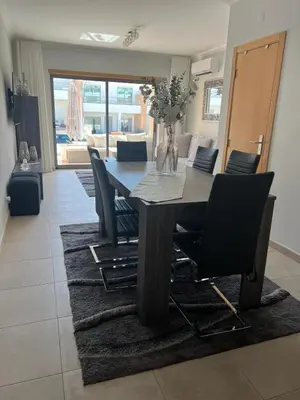 a dining table and chairs in a living room at Vila Branca in Albufeira