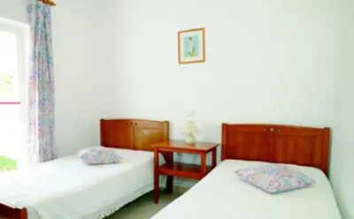 a bedroom with two beds and a table and a window at Villas King's in Albufeira