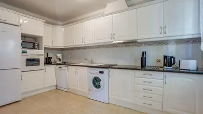 a white kitchen with white cabinets and a dishwasher at Villa Girassol in Vilamoura