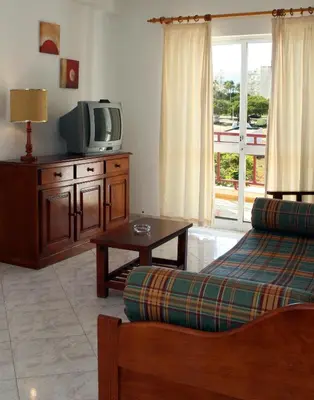 a living room with a couch and a tv at Apartamentos King's in Quarteira