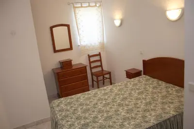 a bedroom with a bed and a dresser and a chair at Apartamentos King's in Quarteira