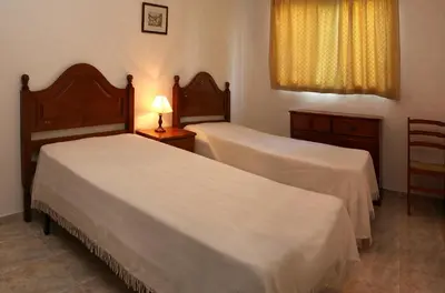 a bedroom with two beds and a lamp and a window at Apartamentos King's in Quarteira