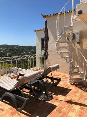 a lounge chair and an umbrella on a deck at Felicidade in Loulé