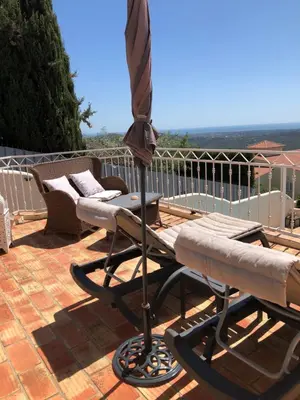 a patio with a table and an umbrella and chairs at Felicidade in Loulé