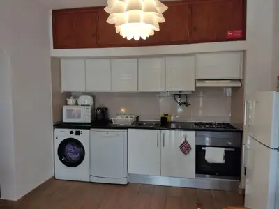 a kitchen with white cabinets and a washer and dryer at Vieira apartment 1 in Quarteira