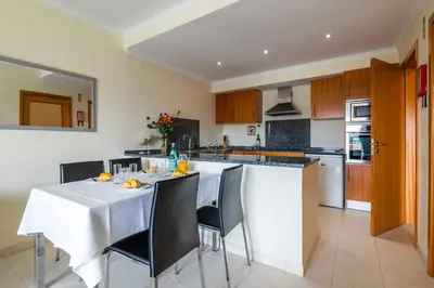a kitchen with a table with chairs and a white counter at Vista das Ondas by Algarneto in Albufeira