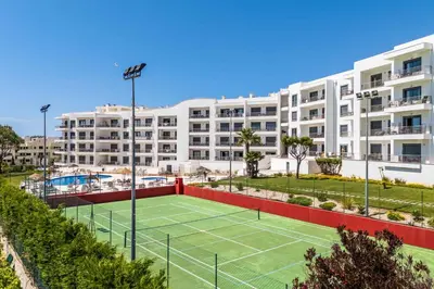 a tennis court in front of a large building at Vista das Ondas by Algarneto in Albufeira