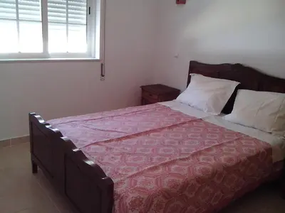 a bedroom with a bed with a red comforter and a window at Albufeira 1 bedroom apartment 5 min from Falesia beach and close to center E in Albufeira