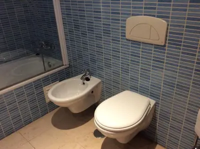 a blue tiled bathroom with a toilet and a sink at Corcovada in Albufeira