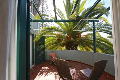 a balcony with two chairs and a palm tree at Villa Bonito 56 - Clever Details in Vilamoura