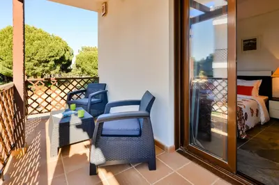 a balcony with chairs and a bed and a window at Falesia Beach A in Roja- Pé