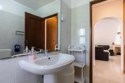 a white bathroom with a sink and a living room at Akisol Olhos de Agua Pine II in Albufeira