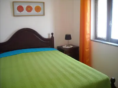 a bedroom with a green bed and a window at Vivenda João Damas in Albufeira