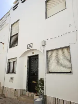 a white building with a black door and windows at Vivenda João Damas in Albufeira