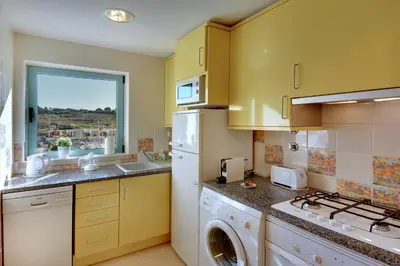a kitchen with yellow cabinets and a washer and dryer at Marina Bay Residence in Albufeira