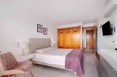 a bedroom with a bed and a chair and a sink at Apartamento Varandas do Mar, Praia dos Pescadores, Albufeira in Albufeira