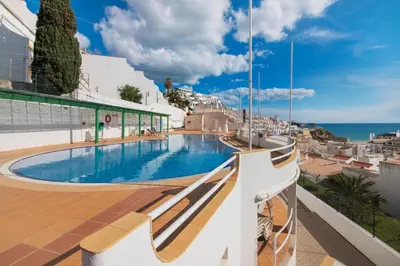 a swimming pool on the roof of a building overlooking the ocean at Apartamento Varandas do Mar, Praia dos Pescadores, Albufeira in Albufeira