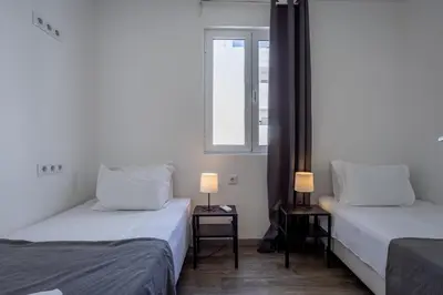 two beds in a room with a window at Hostellicious in Faro