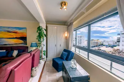 a living room with a couch and a large window at Blue Boat in Quarteira