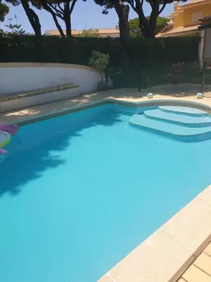 a large blue swimming pool in a yard at The Pinewood Villa in Vilamoura