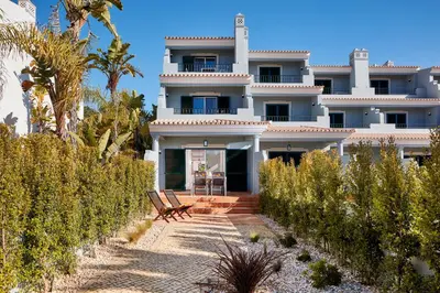 a large white house with palm trees in front of it at Ancão Gardens in Quinta do Lago
