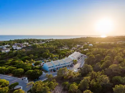 an aerial view of a resort with trees and the ocean at Ancão Gardens in Quinta do Lago
