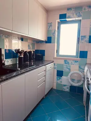 a kitchen with white cabinets and blue tiles at Beautiful Apartment In Albufeira Marina in Albufeira