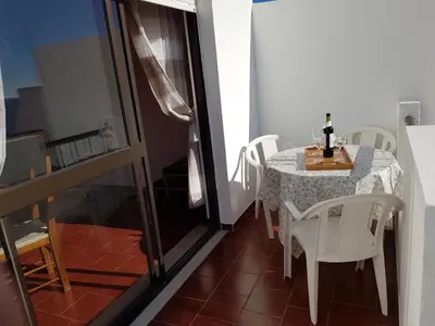 a table with white chairs and a bottle of wine on it at Apartamento Correia in Albufeira