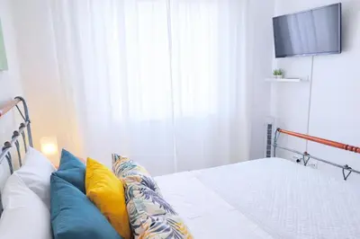 a white bedroom with a bed and a mirror at Avenue Apartment in Quarteira