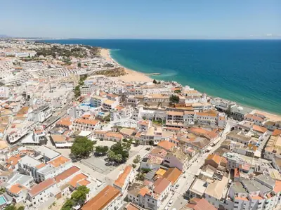 a white building with a blue stripe on it at ETHOS Bertolina Wellness Urban Living in Albufeira