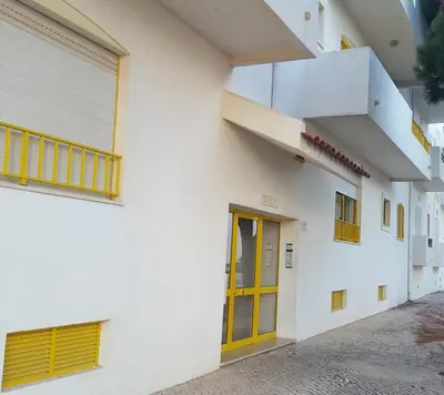 a white building with a yellow door and stairs at GelbBlau Falésia in Albufeira