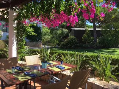a wooden table and chairs in a garden with pink flowers at Algarve Luxury Experience - Situated within the Pinecliffs Resort in Albufeira