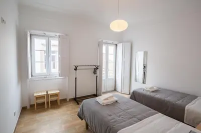 a room with two beds and a table and two windows at 1977 in Faro