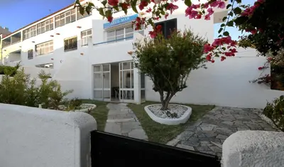 a white building with a tree in a yard at Apartamentos Azul Mar in Albufeira