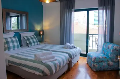 a bedroom with a bed and a chair and a window at Alameda Garden in Faro