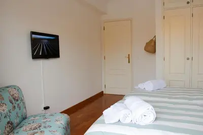 a room with two beds and a chair and a television at Alameda Garden in Faro