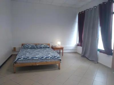 a bedroom with a bed and a table and windows at Melaya Budget Hostel in Faro