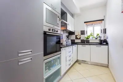a kitchen with white cabinets and stainless steel appliances at Ouranascente in Albufeira