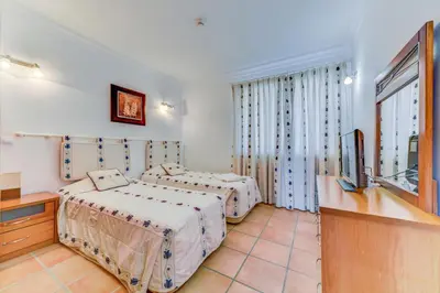 a bedroom with two beds and a flat screen tv at Apartamento Vila Sol com terraço e jacuzzi privad in Quarteira