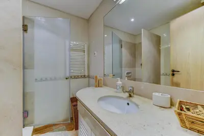 a bathroom with a sink and a large mirror at Apartamento Vila Sol com terraço e jacuzzi privad in Quarteira